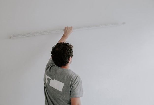 Caucasian plasterer man checks the evenness of the walls after puttying