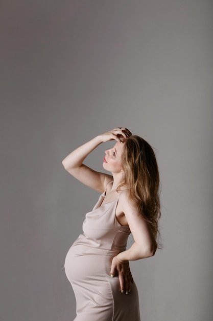 Caucasian pregnant woman stroking her belly on white background copy space