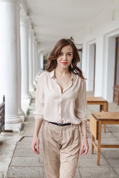 Caucasian pretty girl with red lips curly hair in stylish beige blouse outdoors