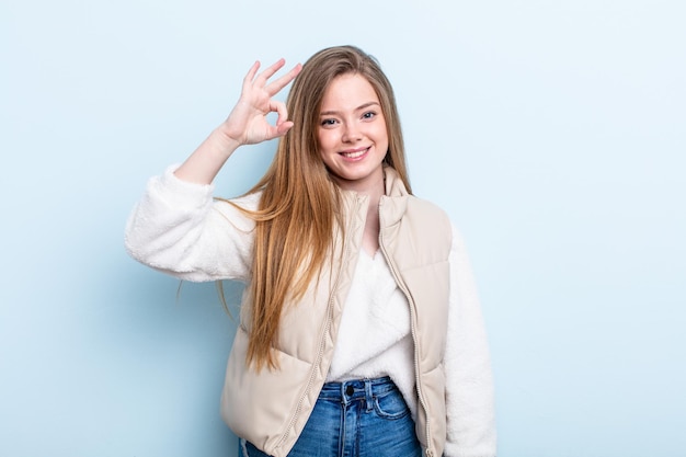 Caucasian red hair woman feeling happy, relaxed and satisfied, showing approval with okay gesture, smiling