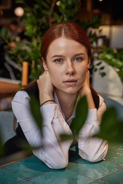 Caucasian redhead pretty girl with long hair sitting at coffee shop table