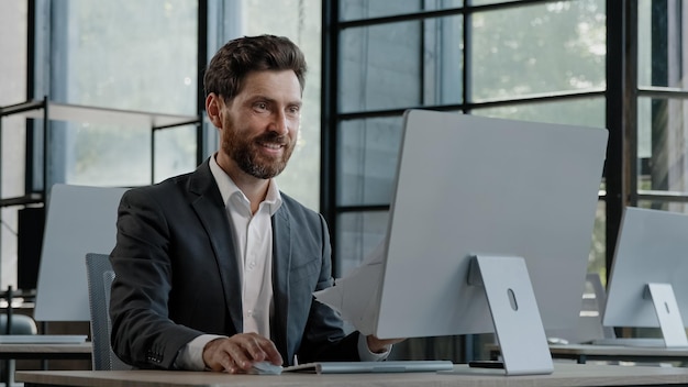 Caucasian s bearded boss investor entrepreneur employer man in office with computer looks at papers