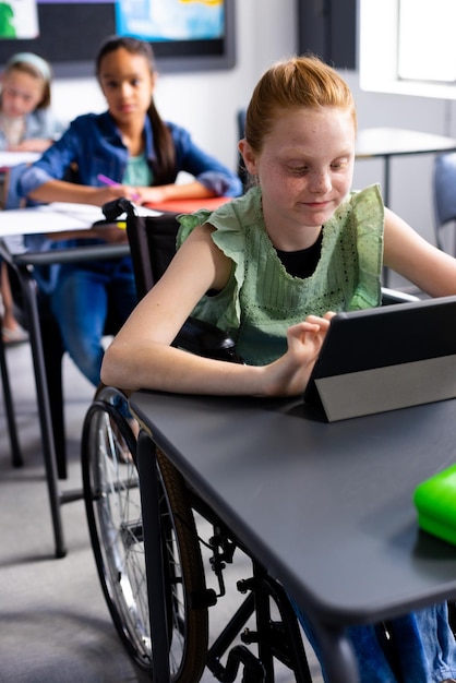 Caucasian schoolgirl in wheelchair with diverse schoolchildren in school classroom