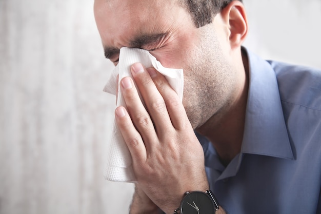 Caucasian sick man blowing his nose.