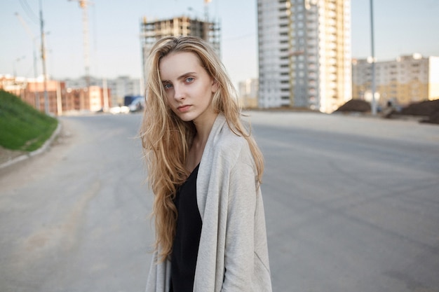 Caucasian skinny female with brown hair outdoors in front of construction site