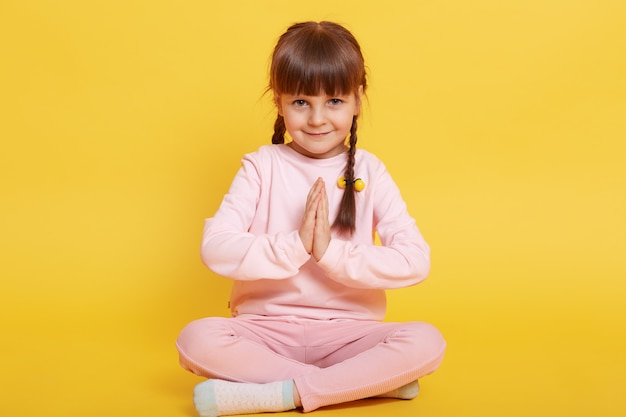 Caucasian small dark haired girl looks at camera with timid smile