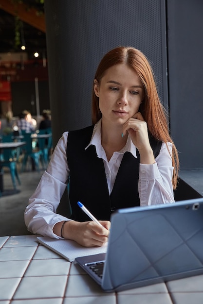 Caucasian student sitting at table of cafe studying with laptop doing homework