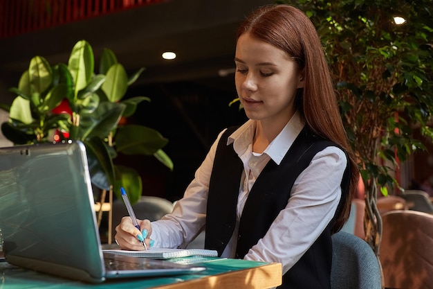 Caucasian student sitting at table of cafe studying with laptop doing homework