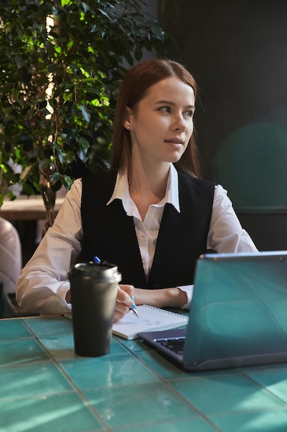 Caucasian student sitting at table of cafe studying with laptop doing homework