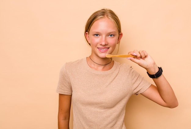 Caucasian teen girl brushing teeth isolated on beige background