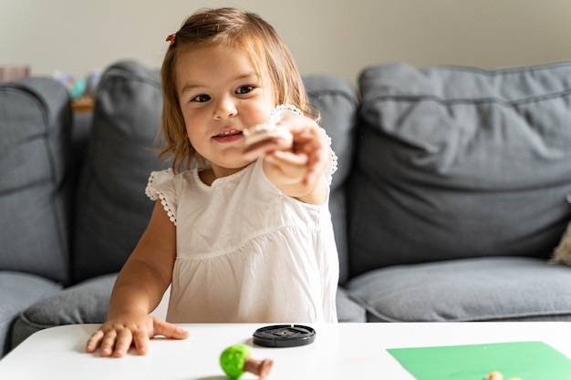 Caucasian toddler girl playing modeling play dough at home with mother.