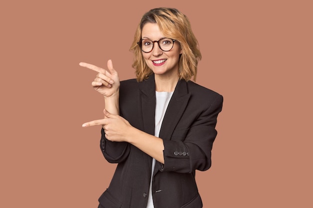 Caucasian woman in black business suit excited pointing with forefingers away