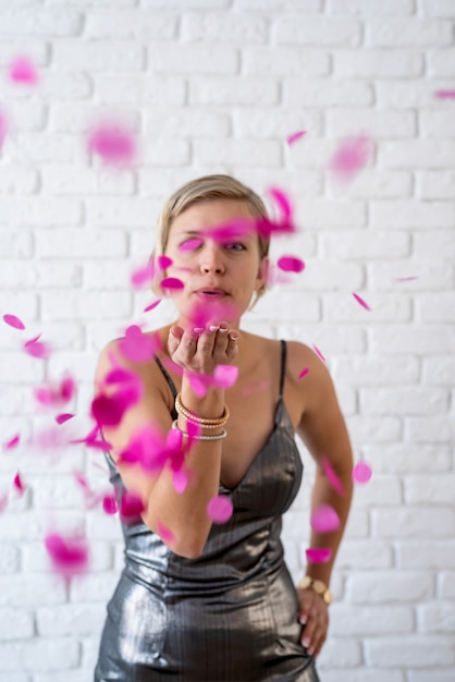 Caucasian woman blowing colorful confetti into the air