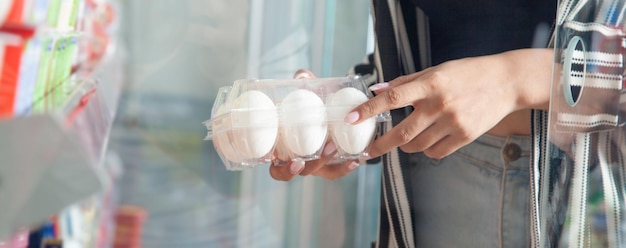 Caucasian woman buying eggs in supermarket