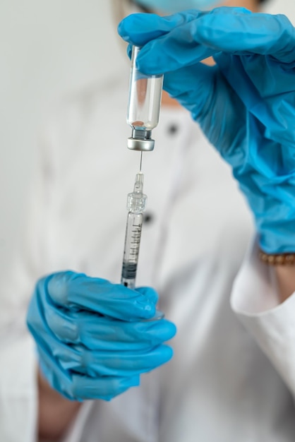 Caucasian woman doctor in white uniform mask gloves holding syringe with vaccine isolated on white