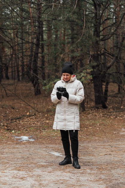 Caucasian woman flying aerial drone in autumn forest.