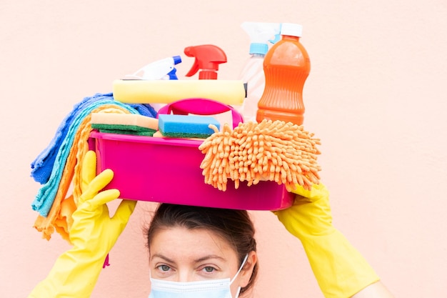 Caucasian woman holding basin with cleaning supplies