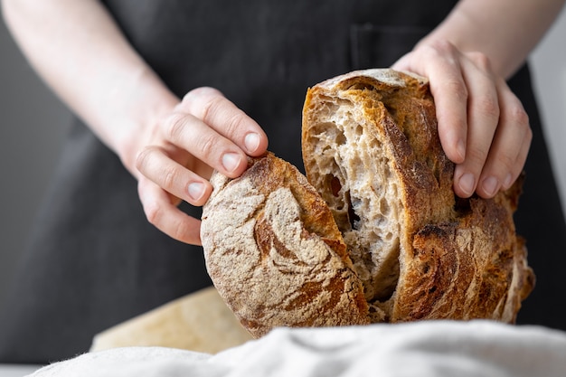 Caucasian woman holding fresh bread from the oven, baking homemade bread, sourdough bread delicious and natural products, healthy food baking, pastry ciabatta