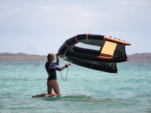 Caucasian woman holding wingfoil in the water