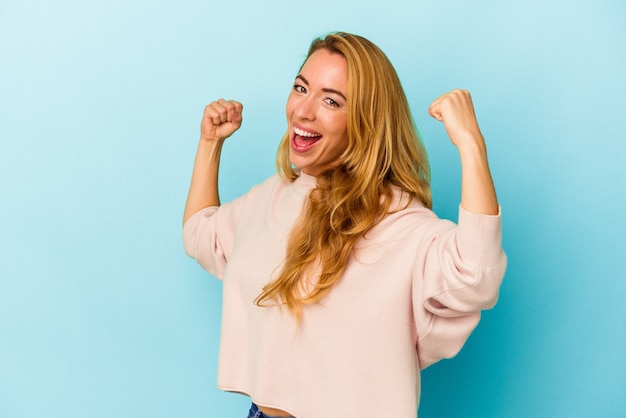 Caucasian woman isolated on blue background cheering carefree and excited. Victory concept.