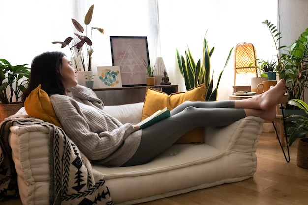 Caucasian woman lying on the couch relaxing reading a book at home. Lifestyle concept.