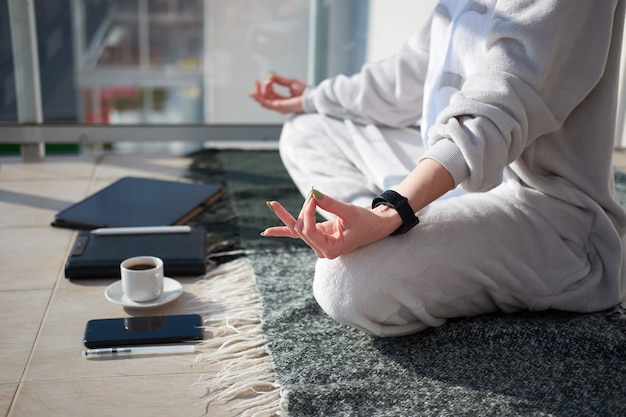 Caucasian woman meditating on balcony in pajamas before working on digital tablet as a freelancer