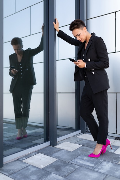 Photo caucasian woman in office clothes waits colleague near office building