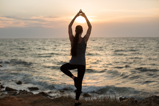 Caucasian woman practicing yoga at seashore of ocean