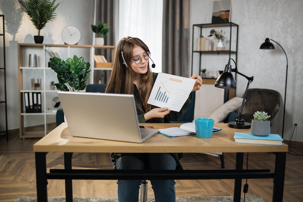 Caucasian woman presenting financial report to colleagues through video call on laptop