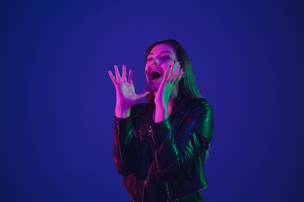 Caucasian woman's portrait isolated on blue studio background in neon light