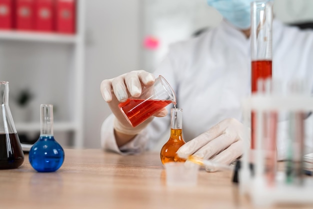 caucasian woman scientist mixed liquid from flask into beaker