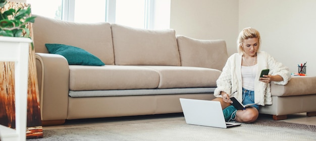 Caucasian woman search learning content online using phone writing up thesis to copybook sitting on ...