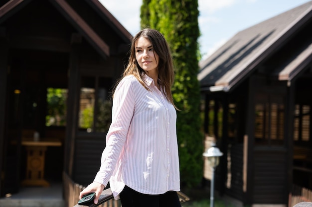 Caucasian woman stand on garden bridge outdoors near wooden cabins