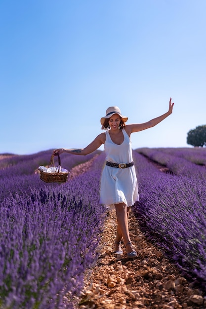 A caucasian woman in a summer lavender field with a hat picking flowers lifestyle