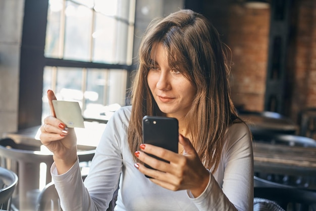 Caucasian woman using credit card with mobile phone for online shopping