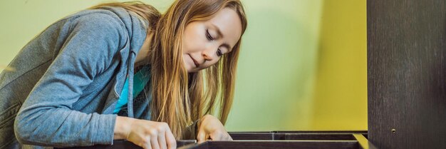 Caucasian woman using screwdriver for assembling furniture banner long format