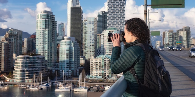 Caucasian Woman with camera taking images of modern cityscape Travel photographer