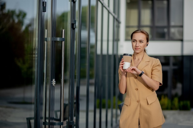 Caucasian woman with smartphone standing against street building background