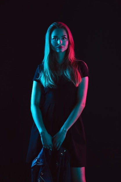 Caucasian womans portrait isolated on dark studio background in neon light