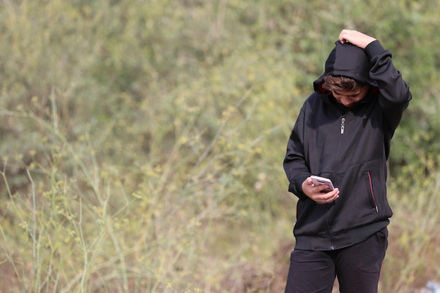 caucasian young boy is walking and using mobile in the forest park way Free Photo