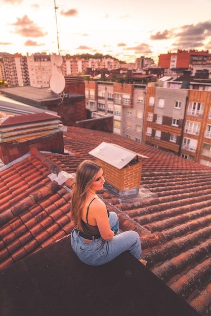 Photo caucasian young girl enjoying sunset with a roofview over donostia-san sebastian, basque country.