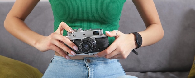 Caucasian young girl holding old camera in home.