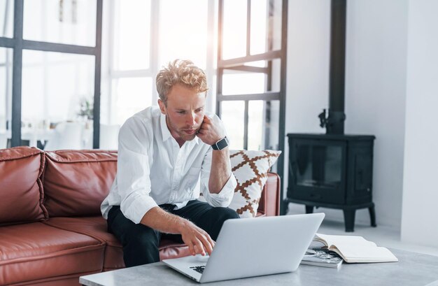 Caucasian young guy in elegant white shirt indoors at home