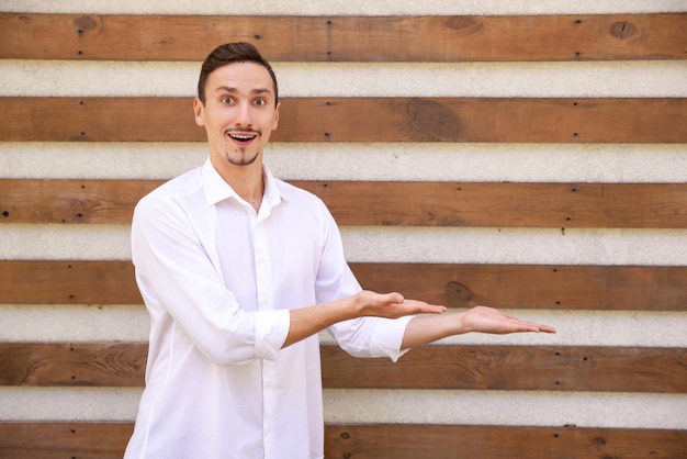 Caucasian young guy in a white shirt holding something on his two paddles on the right side