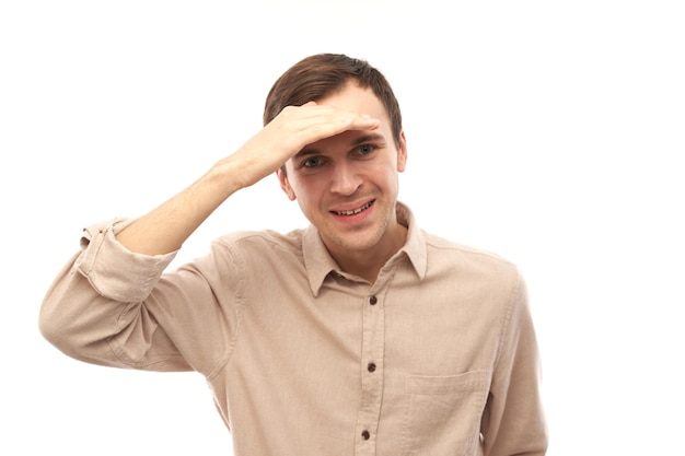 Caucasian young male in casual looks future looking far away distance with hand over head isolated on white background Search concept