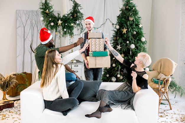 Caucasian young man presenting christmas gifts to friends on the sofa at New Year party