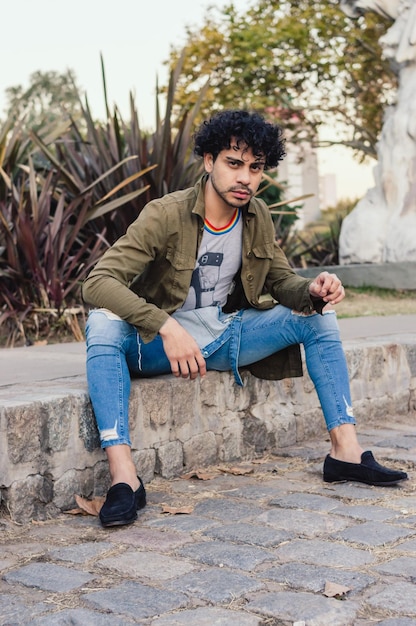 Caucasian young man with curlers outdoors posing sitting in the park