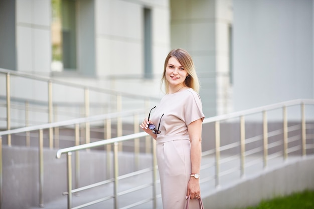 Caucasian young woman in a beautiful dress on the street looks at the camera and smiles