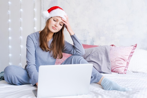 Caucasian young woman while working on laptop at home for Christmas in cozy