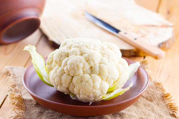 Cauliflower in clay plate on wooden background Organic cauliflower on burlap